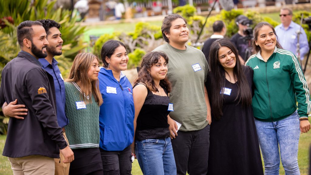 Group of students standing outdoors with arms around each other.